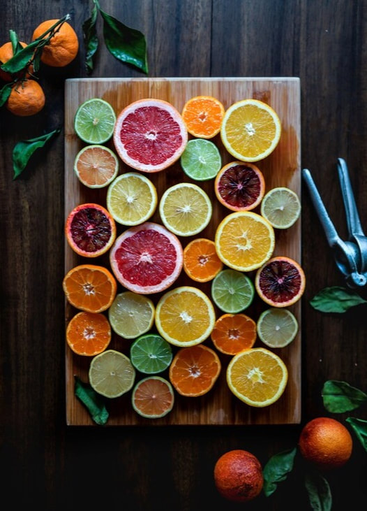 Various slices of citrus arranged on a cutting board on a table next to a lemon squeezer